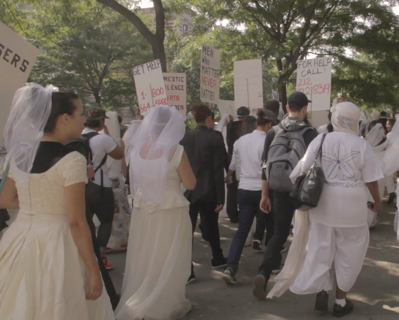 Women in wedding gowns marching with signs.